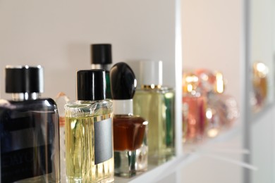 Photo of Different bottles of luxury perfume on shelf in store, closeup