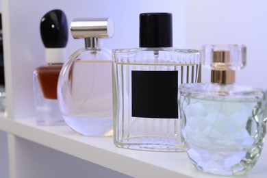 Photo of Different bottles of luxury perfume on shelf in store, closeup