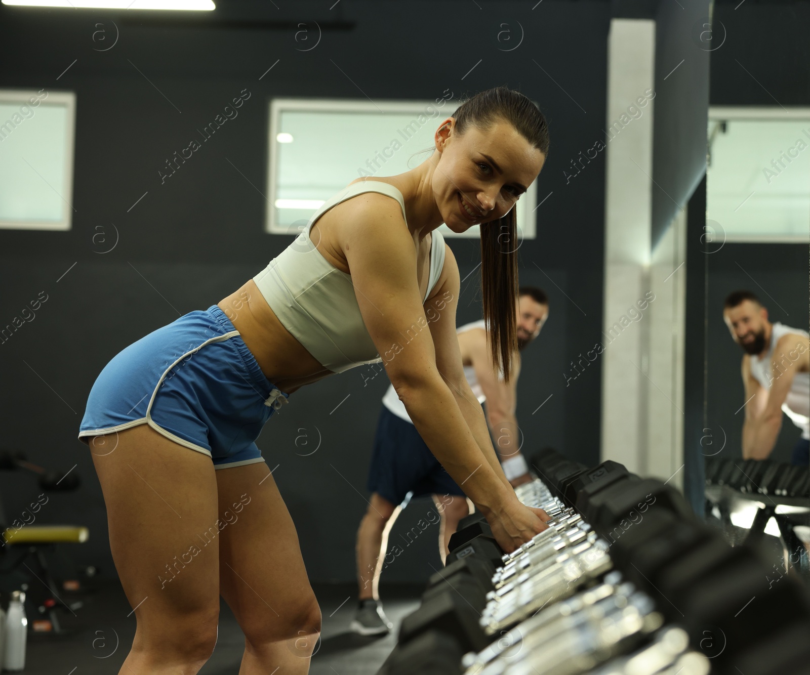 Photo of Athletic woman training with dumbbells in gym