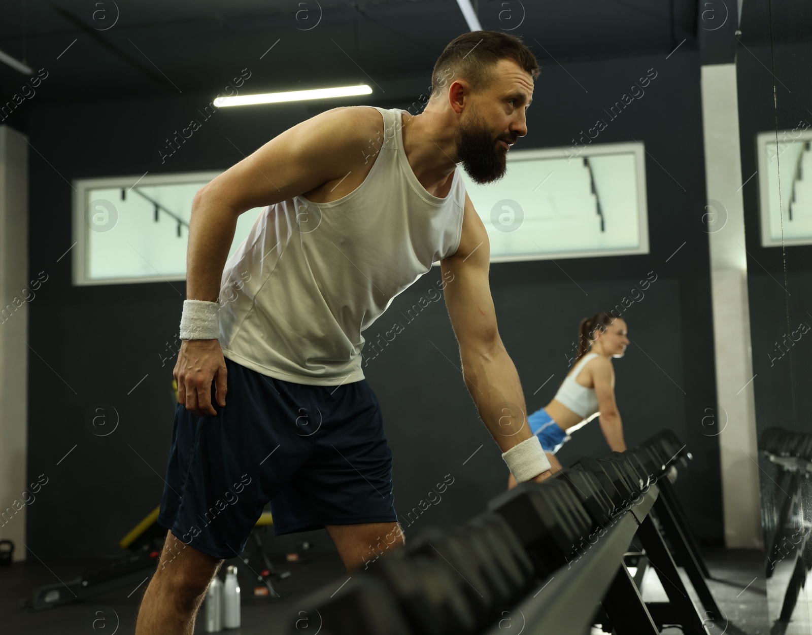 Photo of Athletic man training with dumbbells in gym