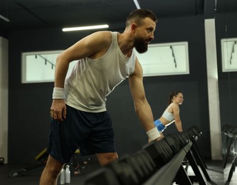 Athletic man training with dumbbells in gym