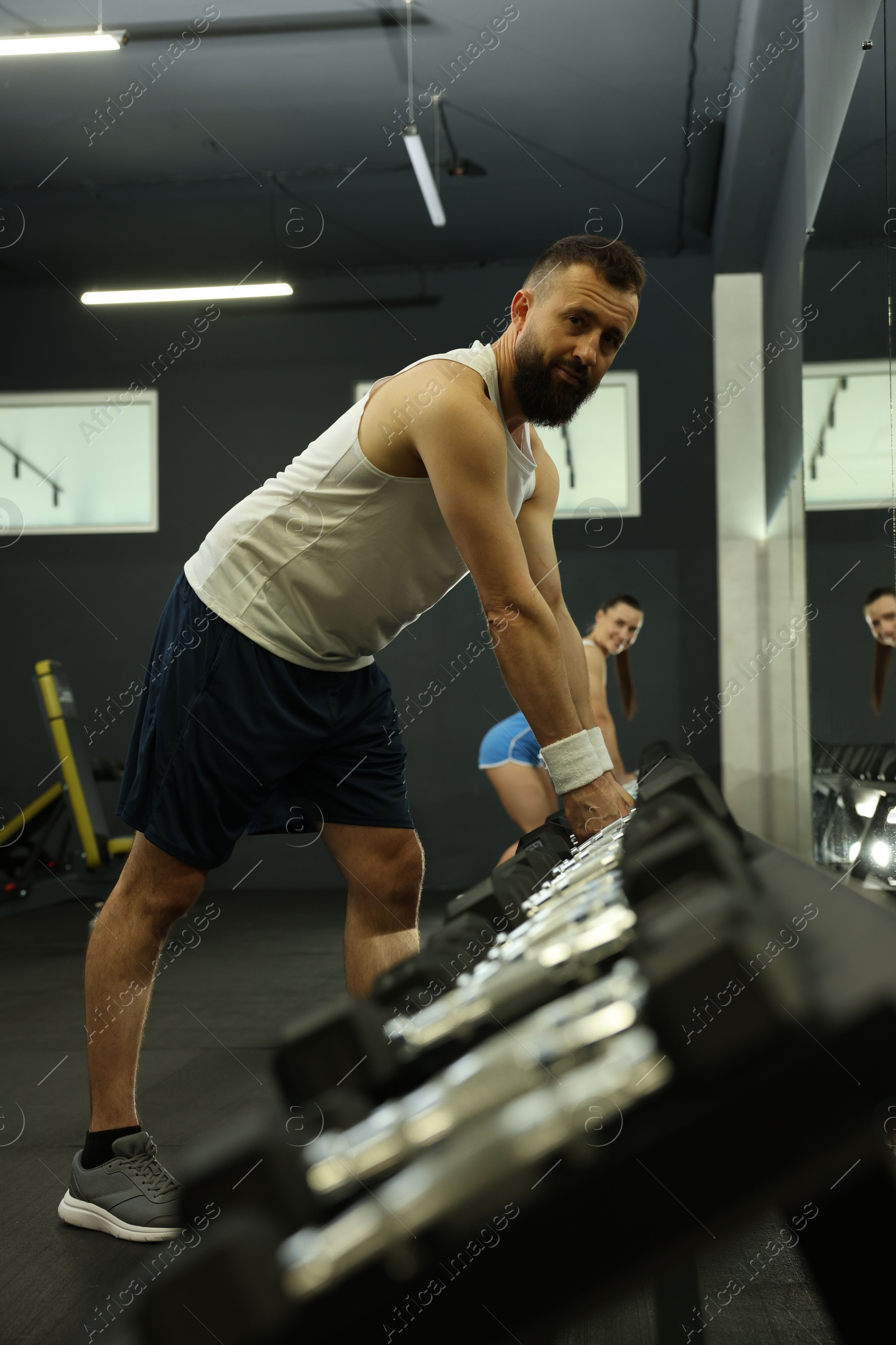 Photo of Athletic man training with dumbbells in gym