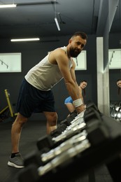 Photo of Athletic man training with dumbbells in gym