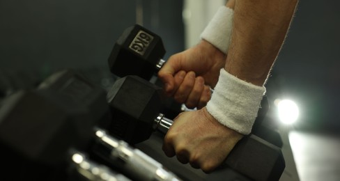 Photo of Athletic man training with dumbbells in gym, closeup