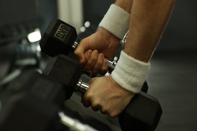 Athletic man training with dumbbells in gym, closeup