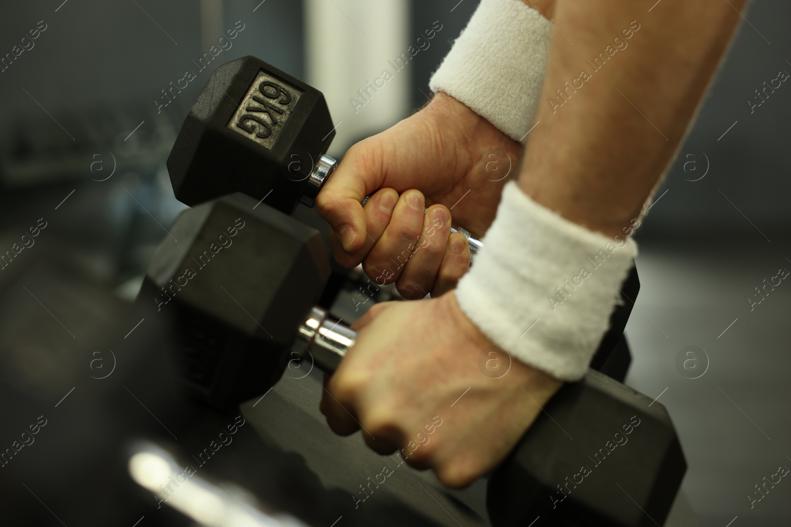 Photo of Athletic man training with dumbbells in gym, closeup