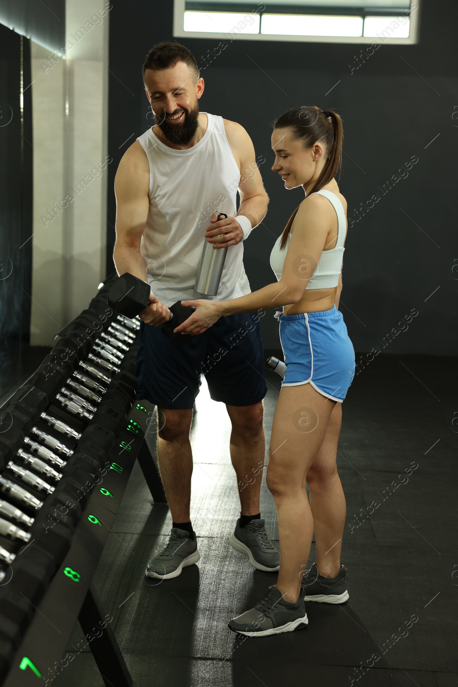 Photo of Athletic couple training with dumbbells in gym