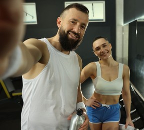 Photo of Couple with water bottles taking selfie after training in gym