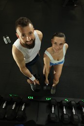 Athletic couple training with dumbbells in gym, above view