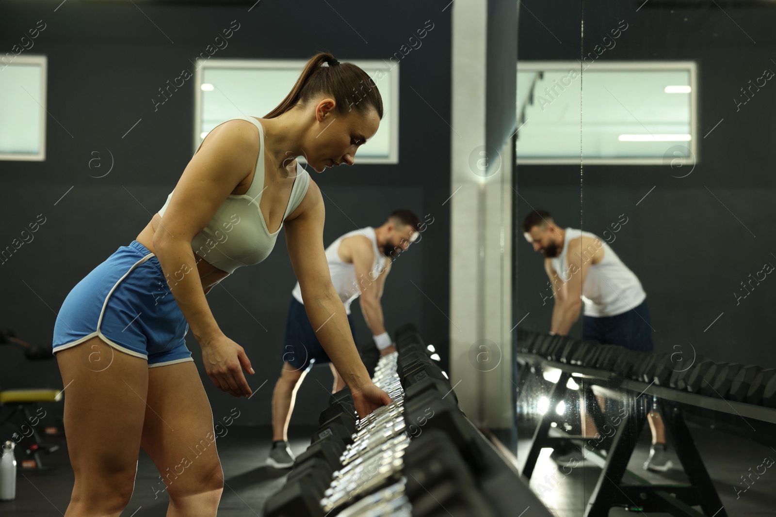 Photo of Athletic woman training with dumbbells in gym