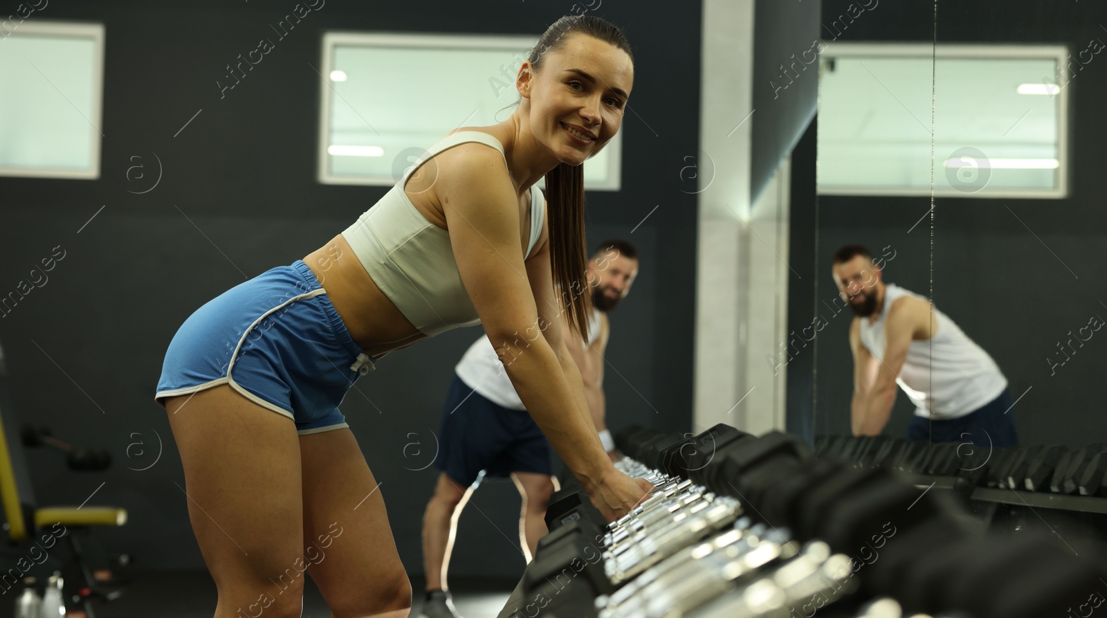 Photo of Athletic woman training with dumbbells in gym