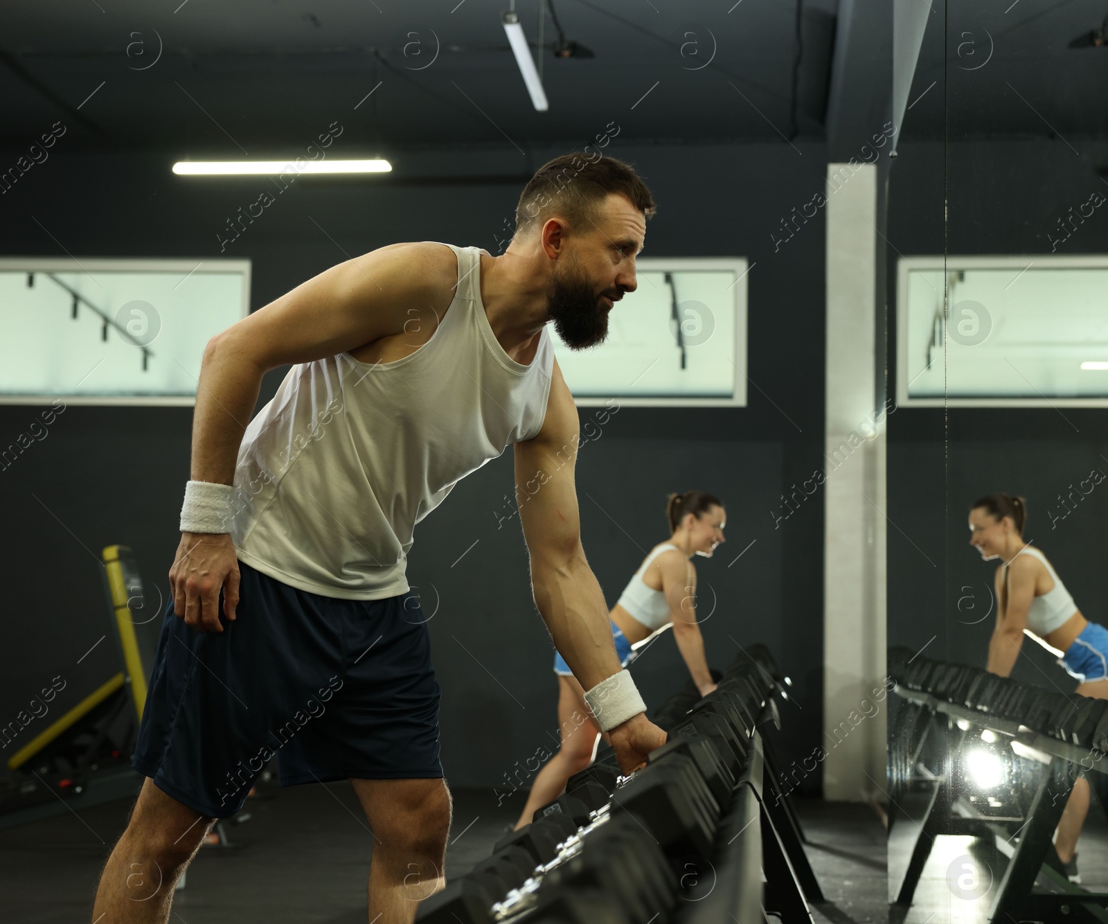 Photo of Athletic man training with dumbbells in gym