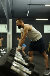 Athletic man training with dumbbells in gym