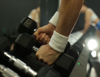 Athletic man training with dumbbells in gym, closeup