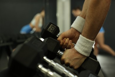 Athletic man training with dumbbells in gym, closeup