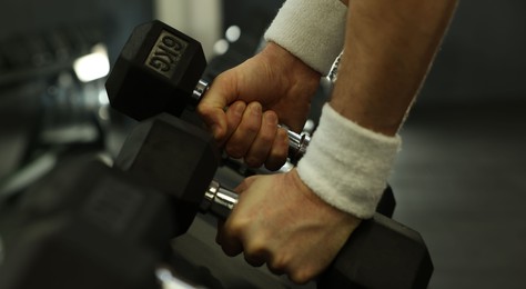 Photo of Athletic man training with dumbbells in gym, closeup