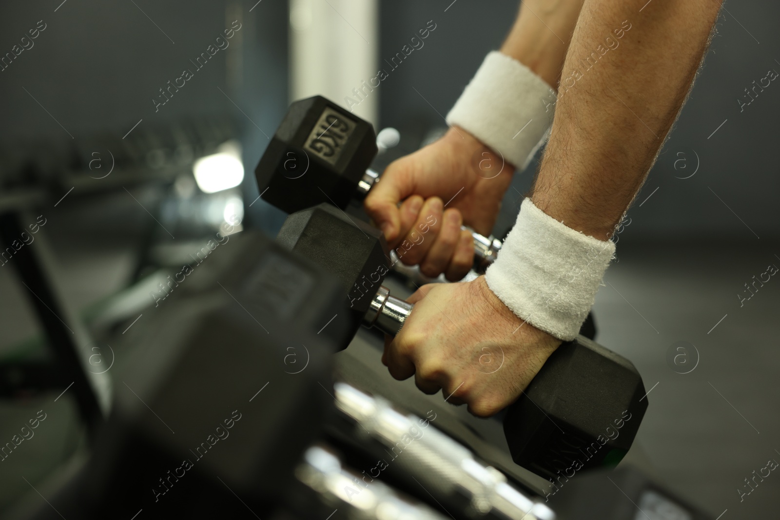 Photo of Athletic man training with dumbbells in gym, closeup