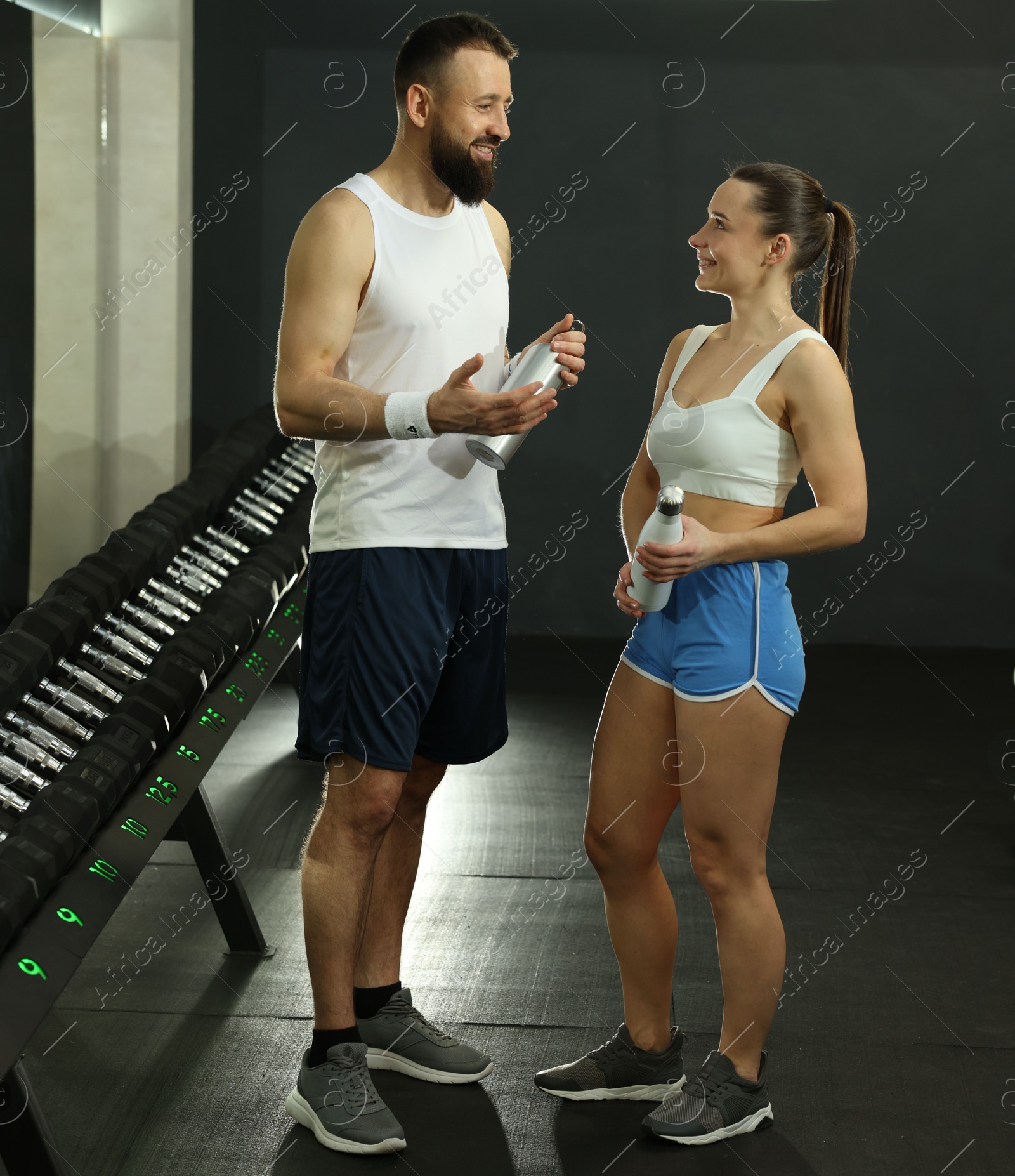 Photo of Athletic couple with water bottles after training in gym