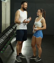 Athletic couple with water bottles after training in gym