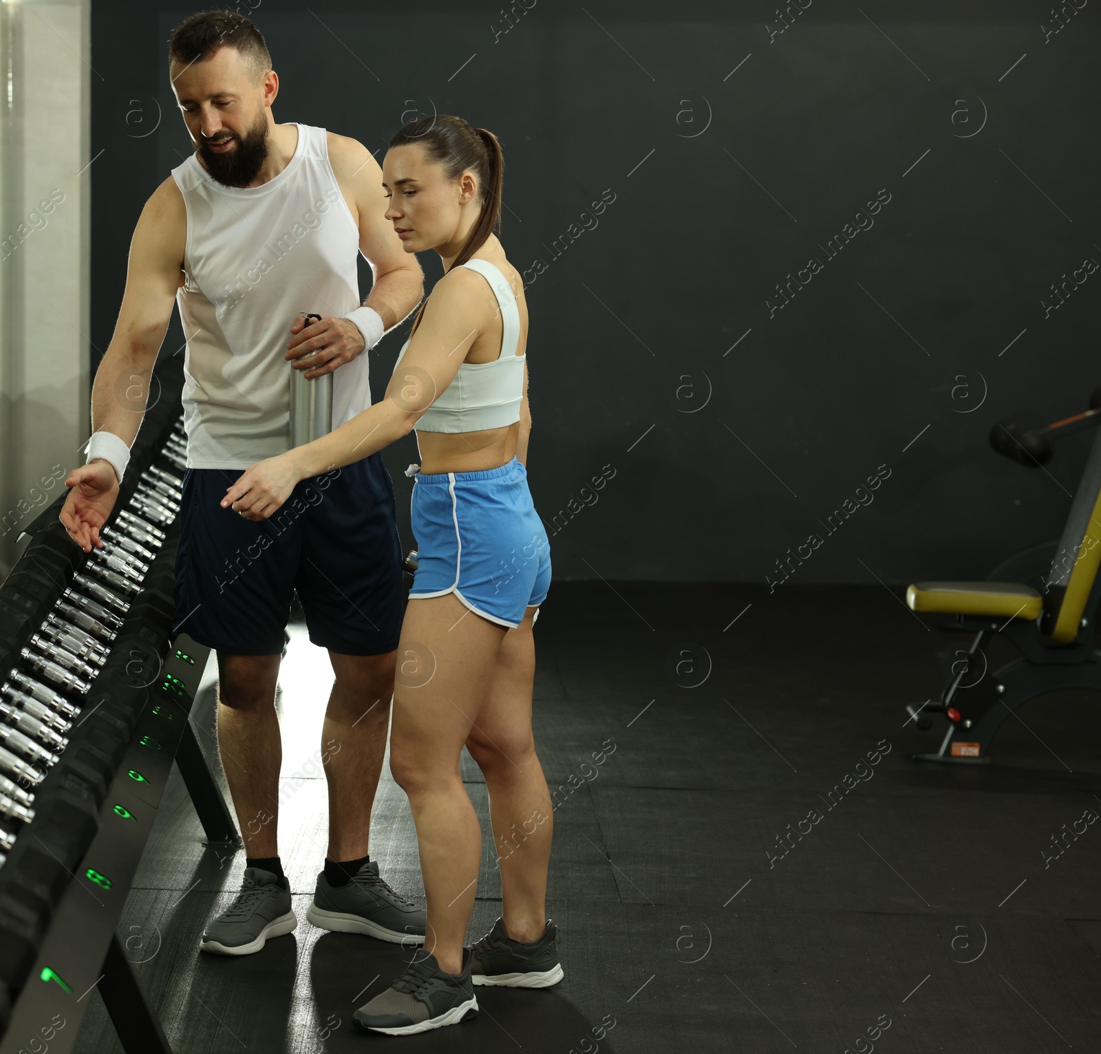 Photo of Athletic couple training with dumbbells in gym