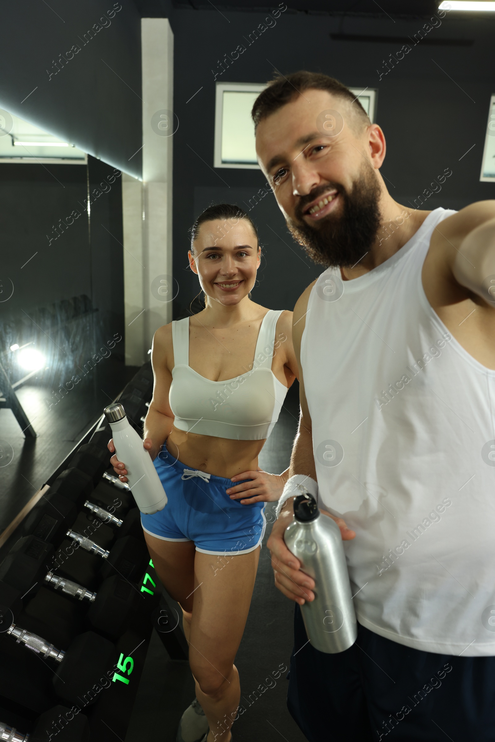 Photo of Couple with water bottles taking selfie after training in gym