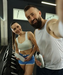 Photo of Couple with water bottles taking selfie after training in gym