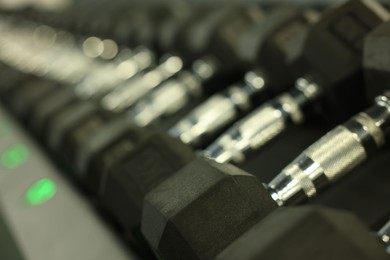 Many dumbbells in gym, closeup. Professional sport equipment