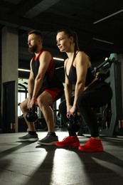 Athletic couple training with kettlebells in gym