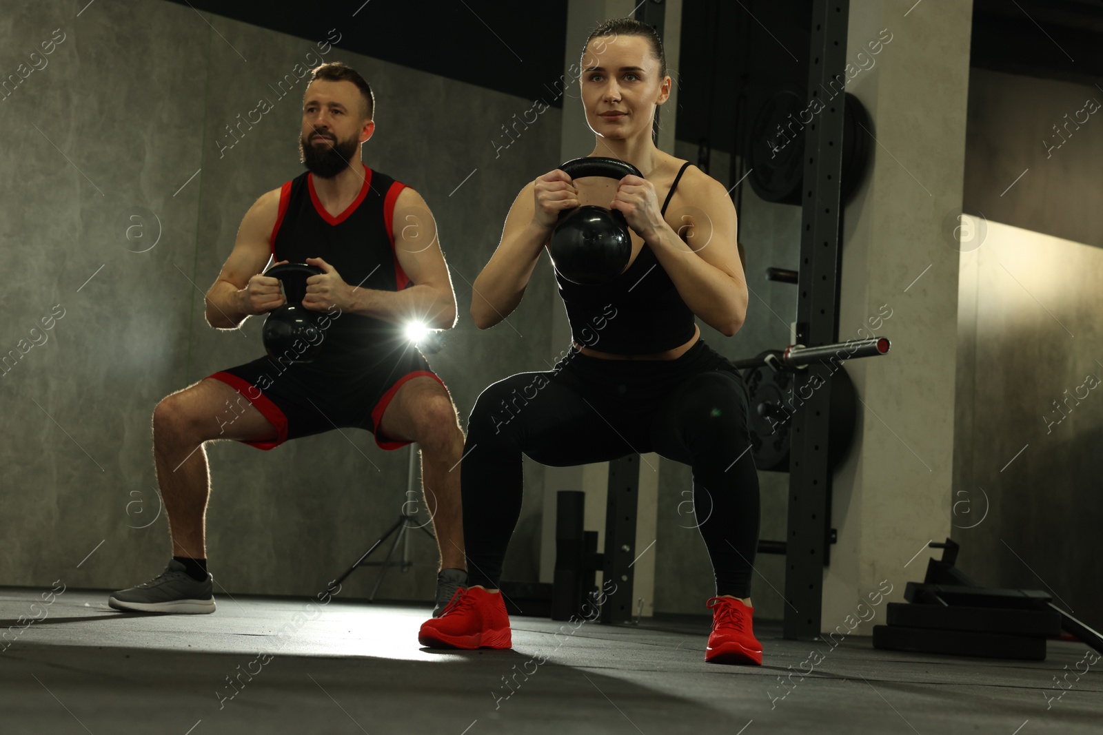 Photo of Athletic couple training with kettlebells in gym