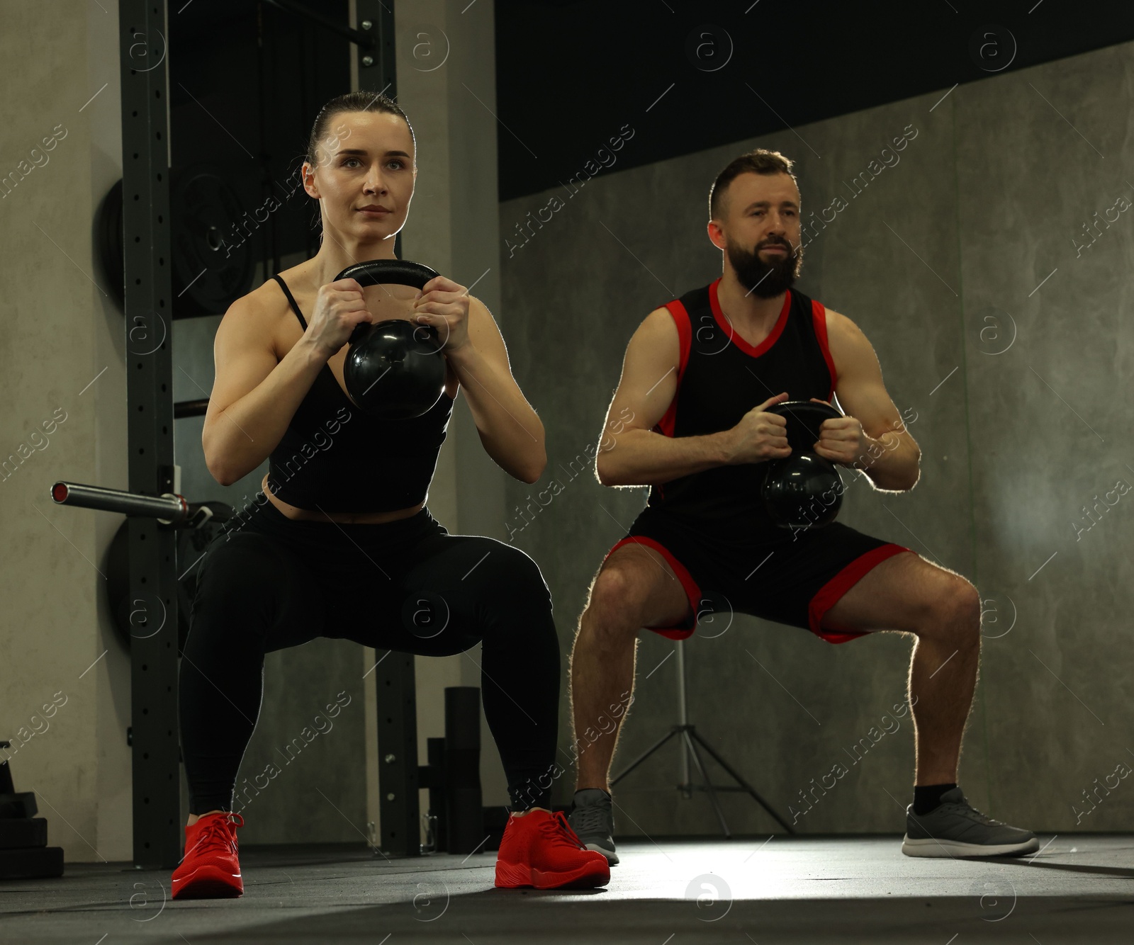 Photo of Athletic couple training with kettlebells in gym