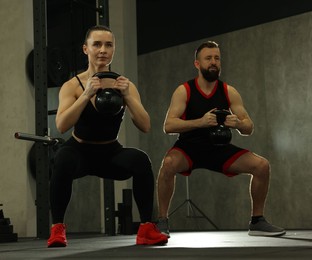 Athletic couple training with kettlebells in gym