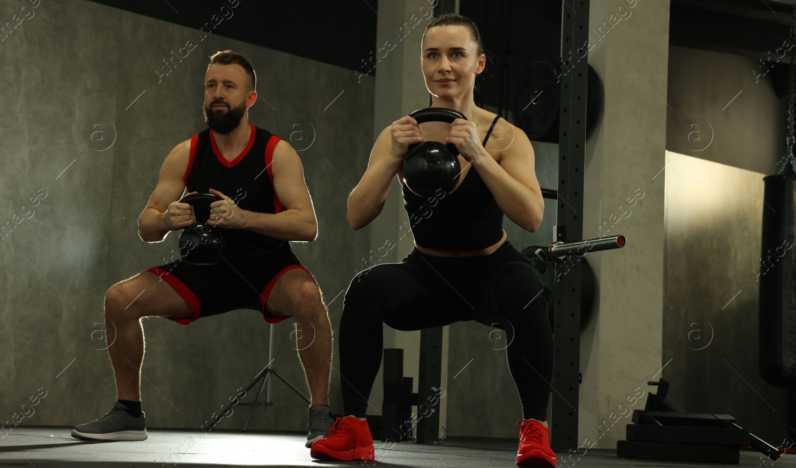 Photo of Athletic couple training with kettlebells in gym