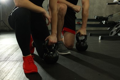 Athletic couple training with kettlebells in gym, closeup