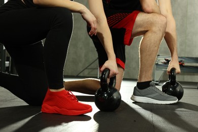 Photo of Athletic couple training with kettlebells in gym, closeup