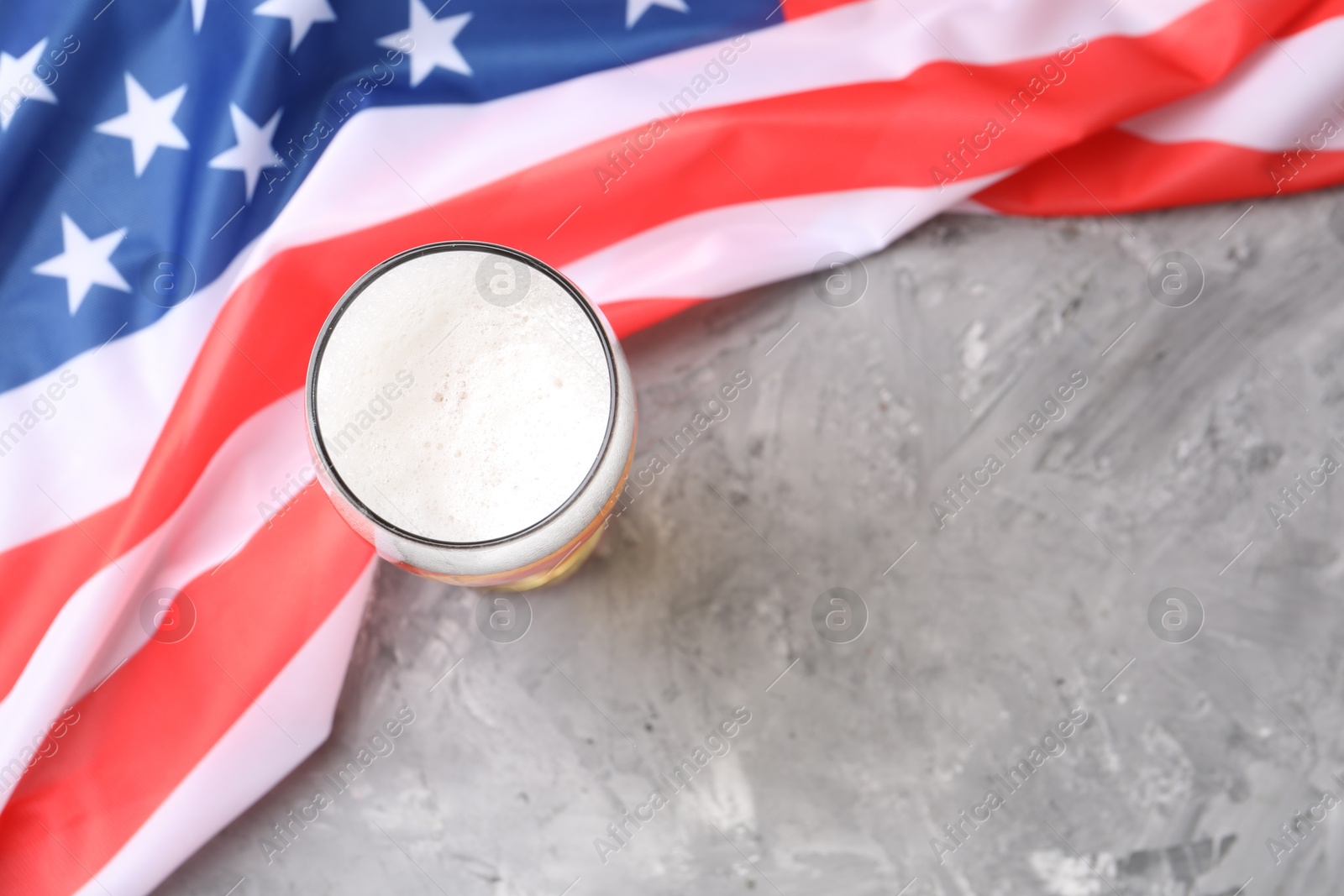 Glass of beer and American flag on grey table, top view. Space for text Photo of Glass of beer and American flag on grey table, top view. Space for text