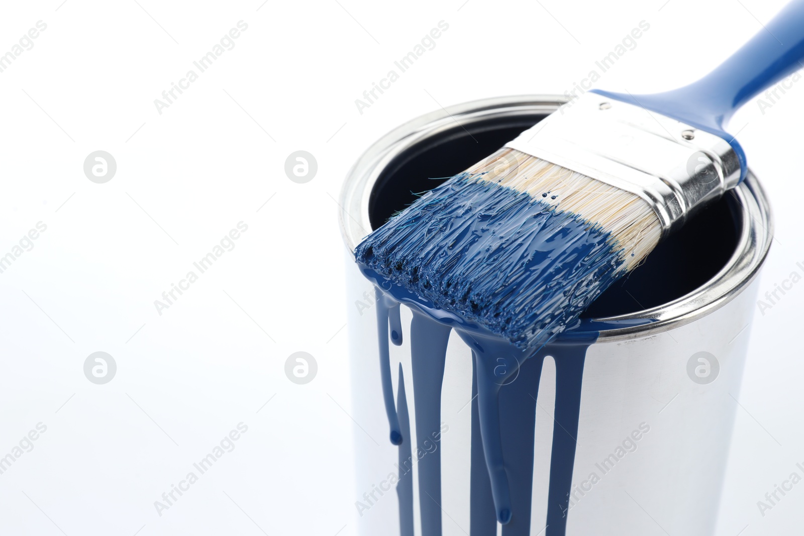 Photo of Can of blue paint and brush on white background