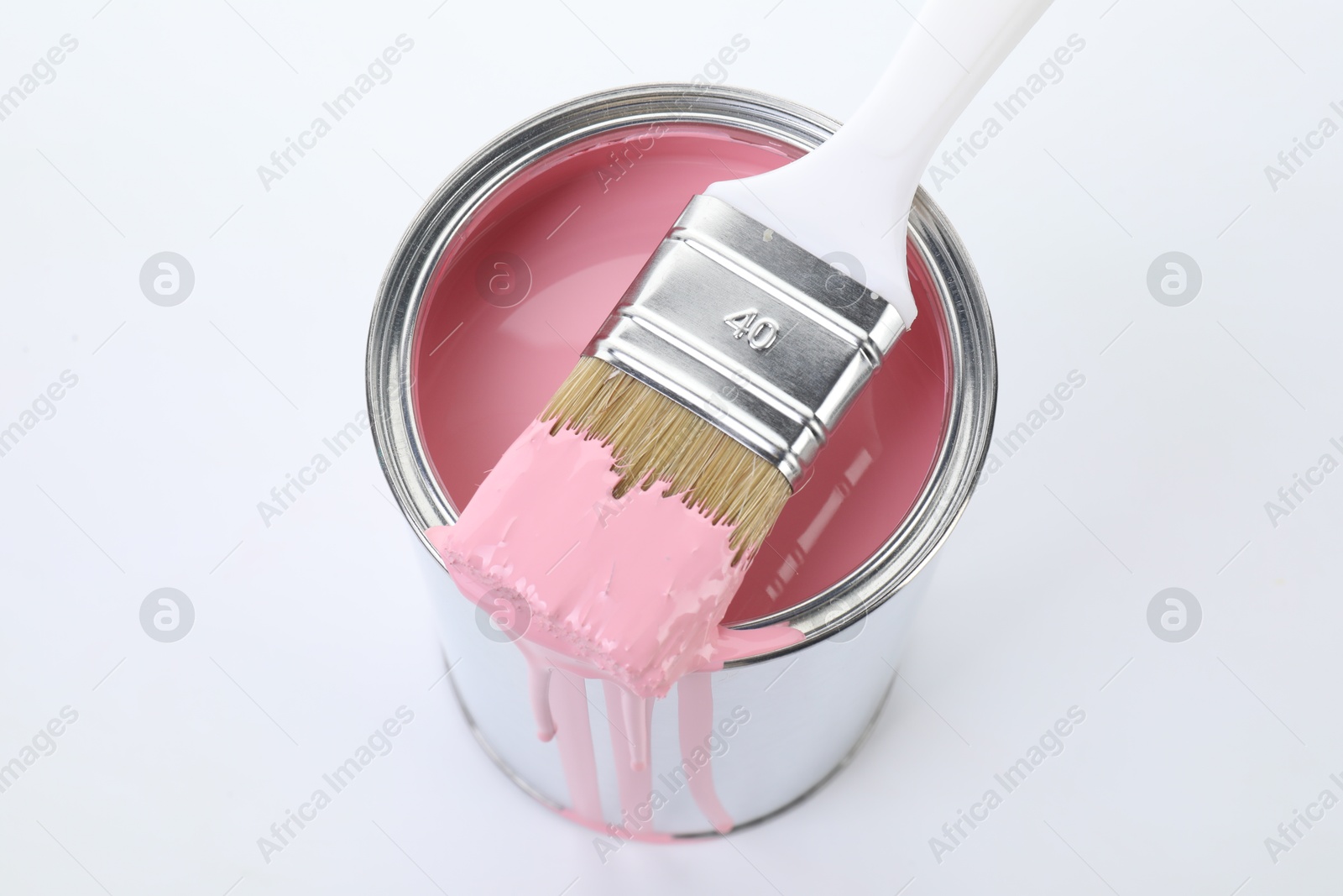 Photo of Can of pink paint and brush on white background