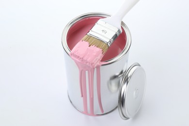 Photo of Can of pink paint and brush on white background