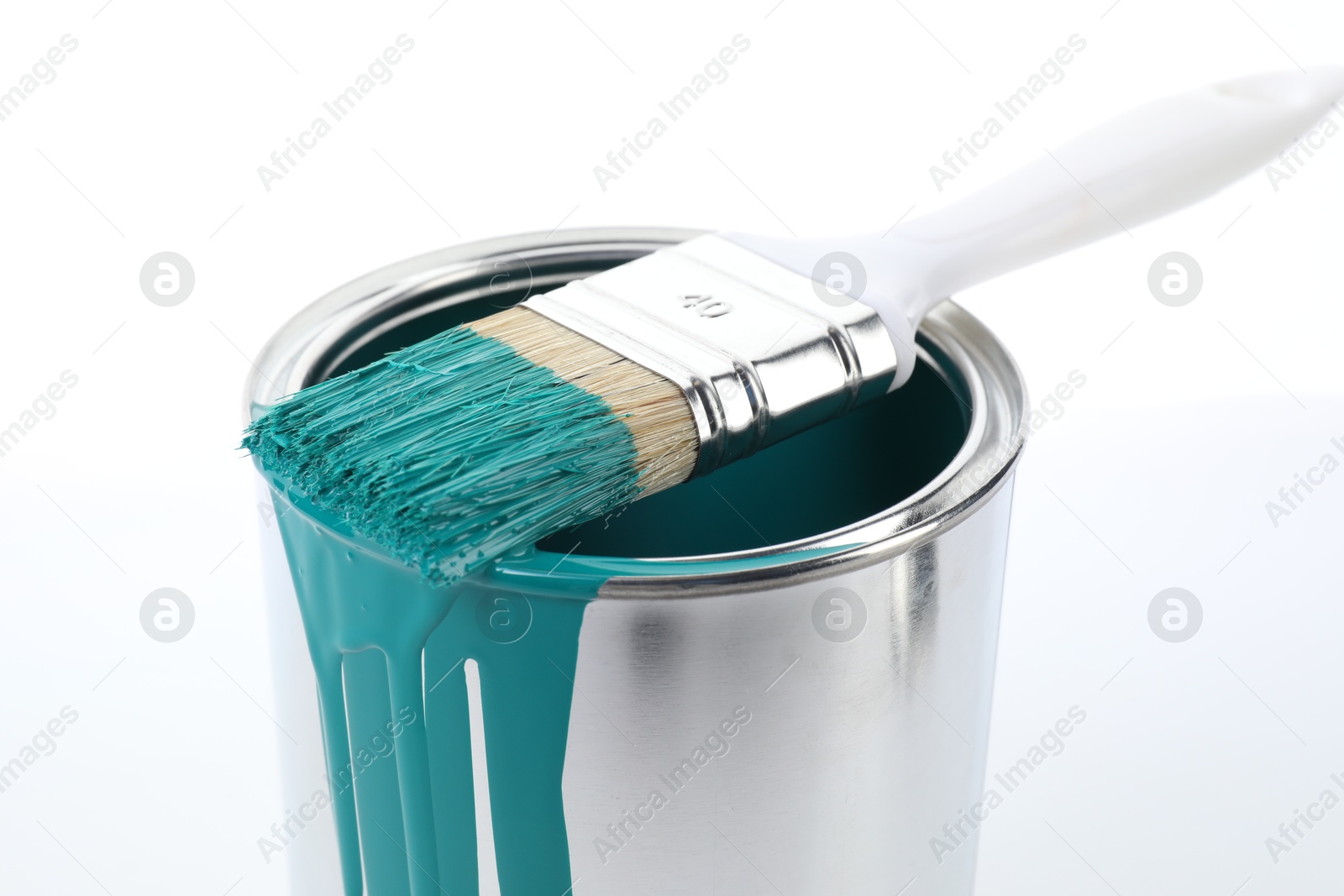 Photo of Can of turquoise paint and brush on white background