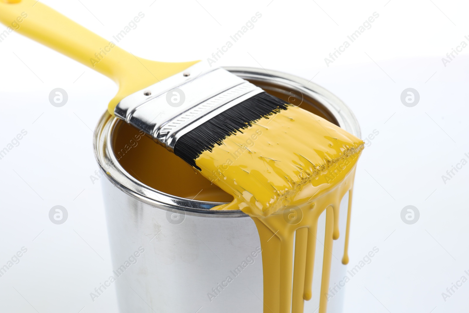 Photo of Can of yellow paint and brush on white background