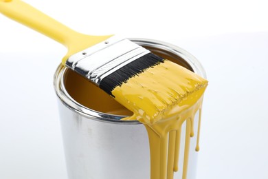 Can of yellow paint and brush on white background