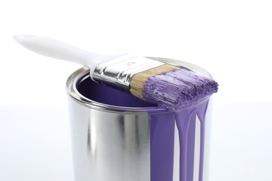 Can of violet paint and brush on white background