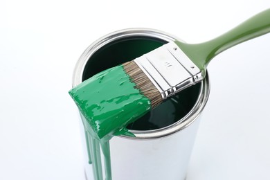 Photo of Can of green paint and brush on white background