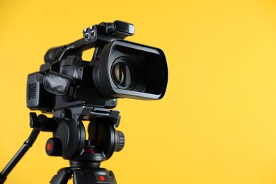 Modern video camera on yellow background, closeup. Space for text