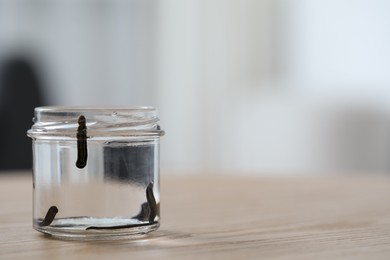 Photo of Medicinal leeches in glass jar on wooden table, closeup. Space for text