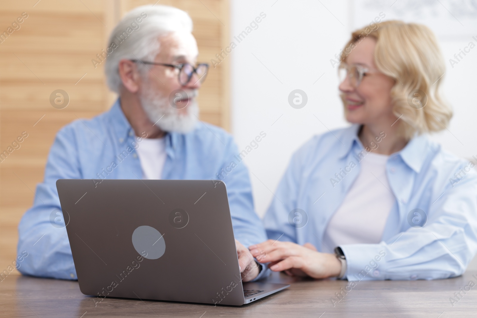 Photo of Senior man and mature woman spending time together at home, focus on laptop. Happy couple