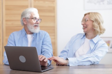 Photo of Senior man and mature woman spending time together at home, focus on laptop. Happy couple