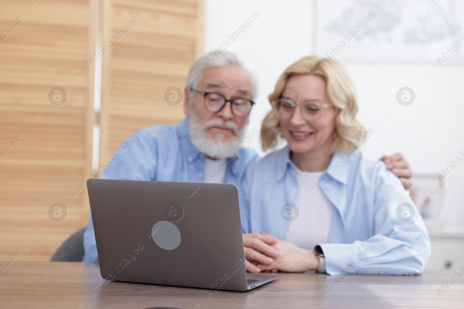 Photo of Senior man and mature woman watching something on laptop at home, selective focus. Happy couple