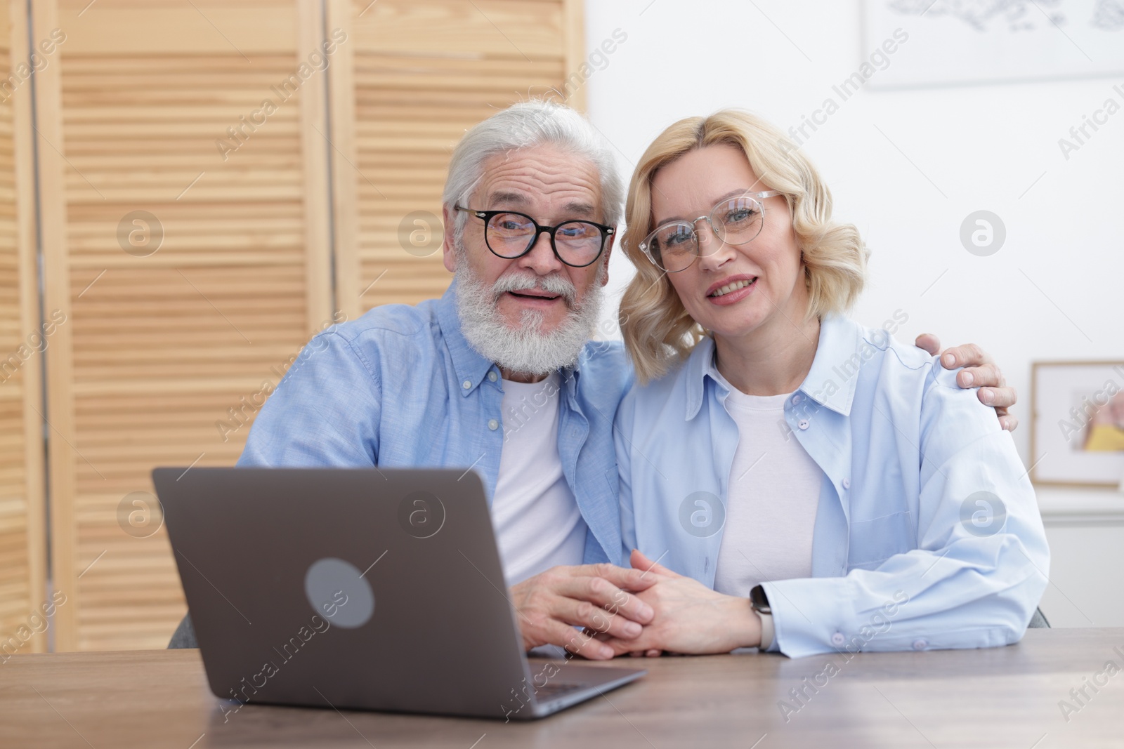 Photo of Senior man and mature woman with laptop at home. Happy couple