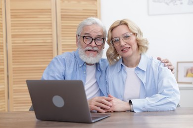 Senior man and mature woman with laptop at home. Happy couple